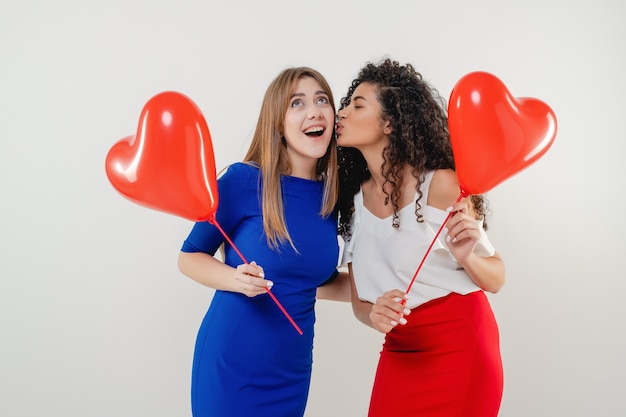 Women with red heart shaped balloons smiling isolated