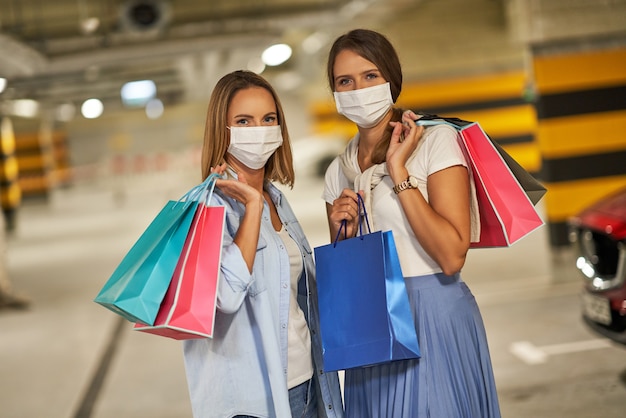 women with shopping bags in masks in underground parking lot
