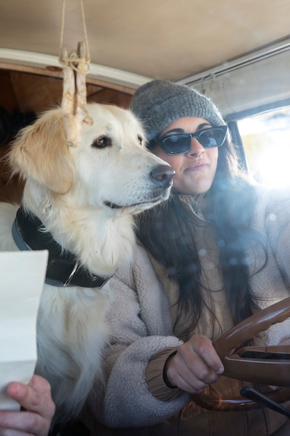 写真 冬時間にキャンピングカーを運転する犬と一緒の女性