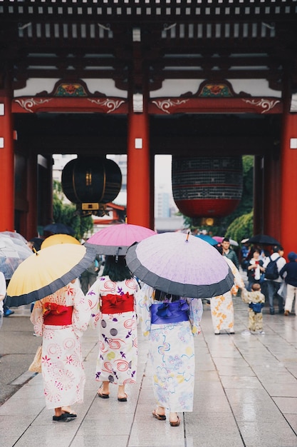 傘を持った女性が寺院に向かって歩いている