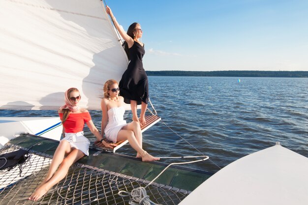 Foto donne su uno yacht, contro uno spazio di vele bianche, mare blu e cielo. concetto di vacanze estive al mare e viaggi.