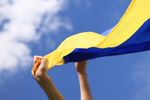 Women039s hands with the Ukrainian flag against the sky Concept war in Ukraine for freedom