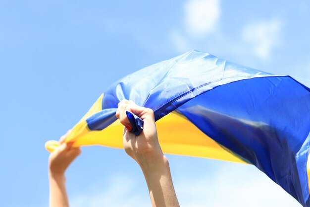 Women039s hands with the Ukrainian flag against the sky The Ukrainian flag is fluttering in the wind