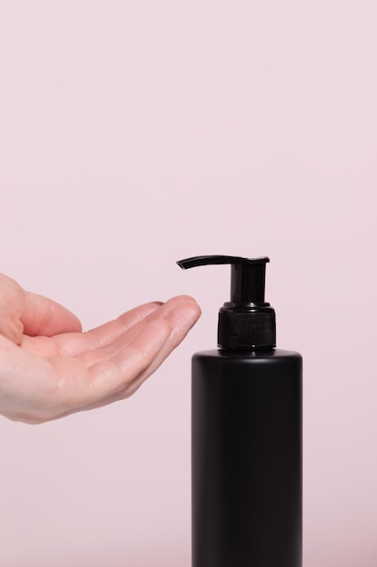 Women39s hands press on a black dispenser with a liquid tonic