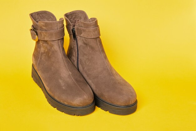 Womens brown suede fashion boots on a yellow background