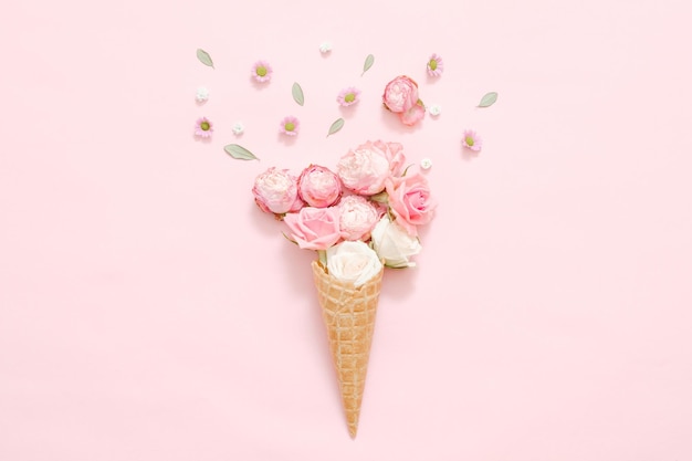 Womens day congratulation Conceptual gift composition Fresh roses in cream cone on pink background