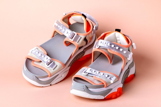 Womens fashionable sports sandals with orange accents on a pink background