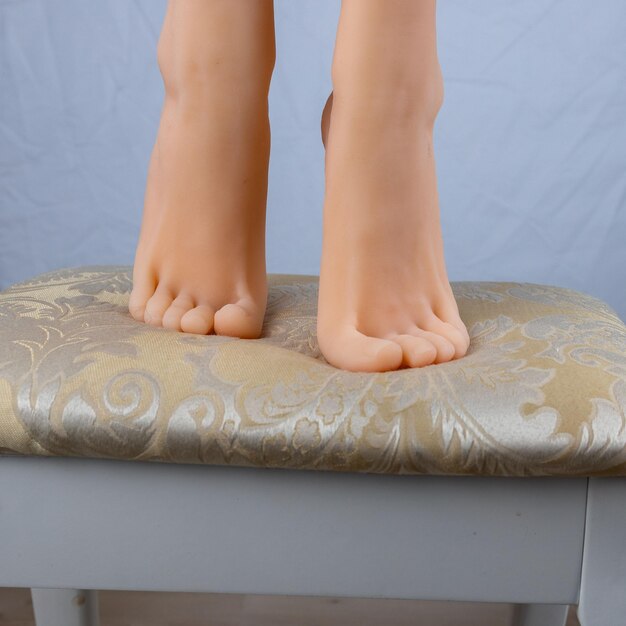 Photo womens feet standing on tiptoes on light fabric chair