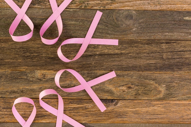 Womens gezondheidssymbool in roze lint op houten bord.