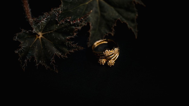 womens gold ring with flowers and leaves and a black background