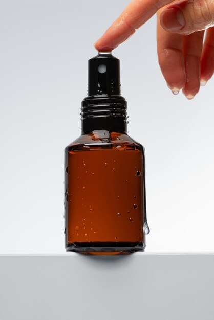womens hand with a brown glass cosmetic jar with a dispenser