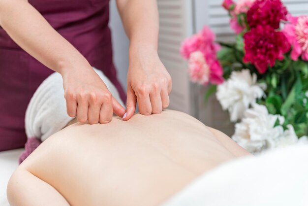 Womens handen doen therapeutische nekmassage voor meisje liggend op de bank in de massage spa Lichaamsverzorging huidverzorging