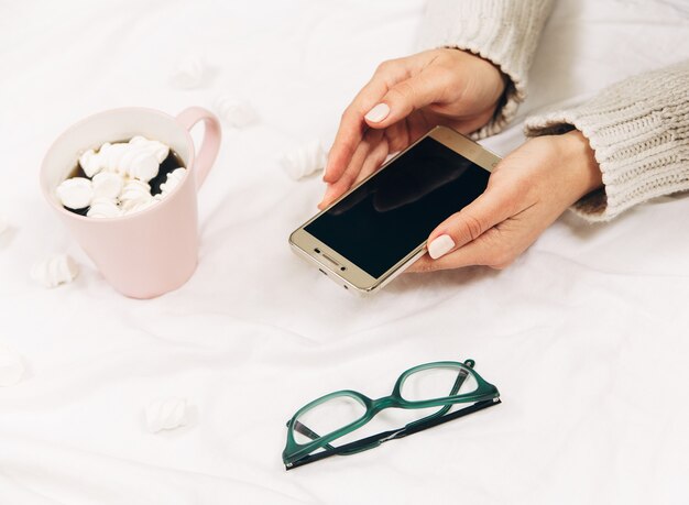 Womens handen met telefoon, koffie en glazen