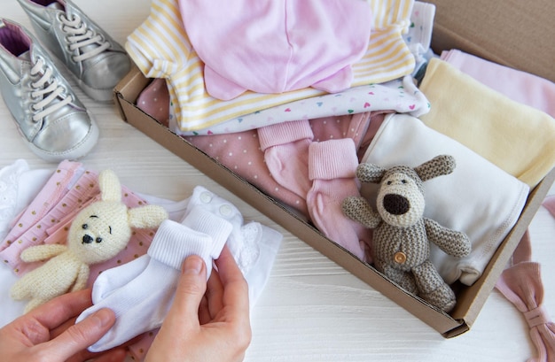 写真 女性の手は子供の服を箱に集めます