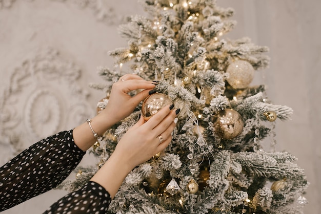 Womens hands decorate the Christmas tree with balloons