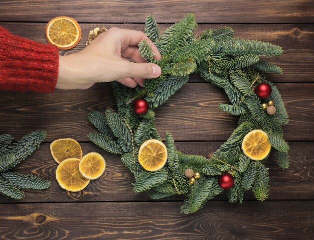 Womens hands decorate a Christmas wreath on a wooden table FLat lay