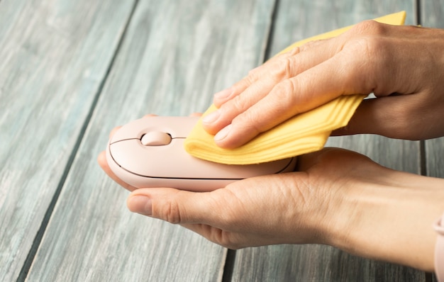 Womens hands disinfect a computer mouse in the office