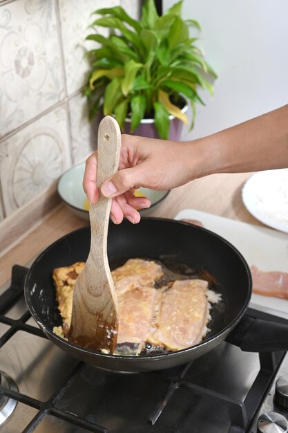 女性の手は、小麦粉と卵で魚を揚げる