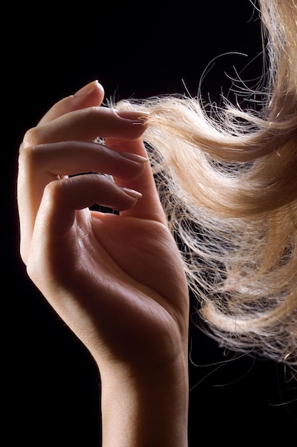 Foto le mani delle donne sui capelli su uno sfondo scuro