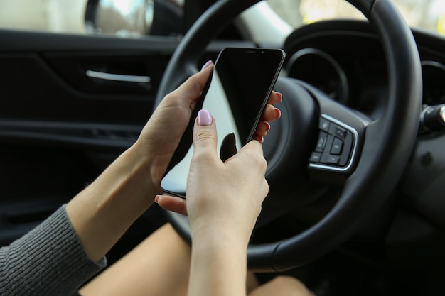 womens hands holding the phone in the car