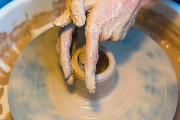 Womens hands of a potter creating an earthen jar