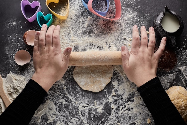 Womens hands roll out the dough with a rolling pin