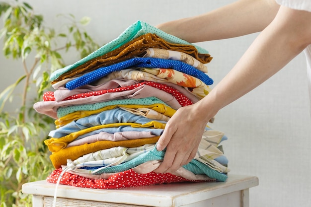 Womens hands take a stack of clothes from the nightstand for laundry or recycling childrens or adult