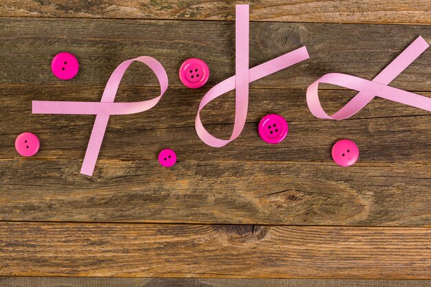 Womens health symbol in pink ribbon on wooden board.