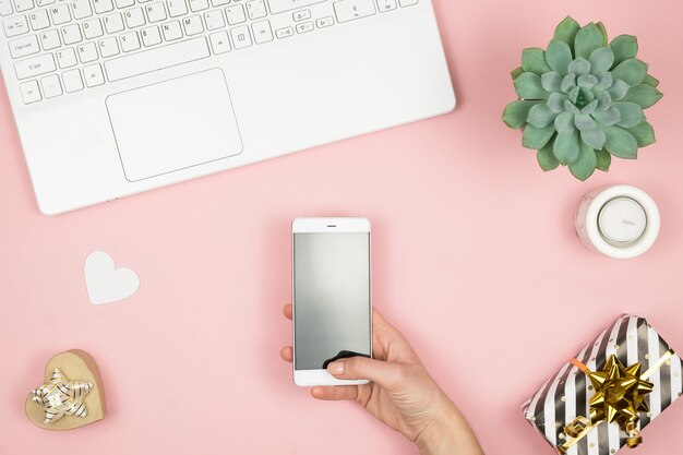 Womens home workspace. Girl Blogger works with phone and laptop. Freelance concept. Teleworker texting using laptop and internet, working online.