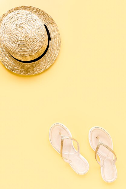 Womens summer traveler accessories straw hat and sandals on yellow background the concept of travel