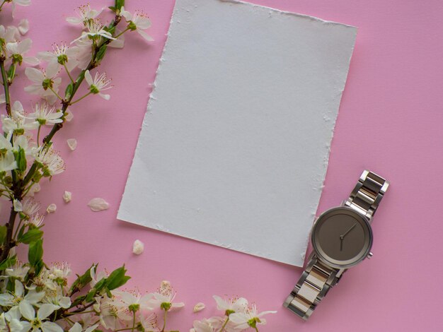 Womens wristwatch on pink background with cherry flowers and copy space