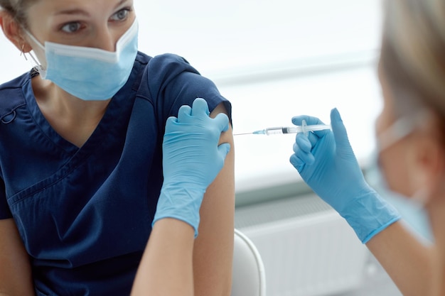 Foto wonan arts of verpleegkundige die injectie of vaccin geeft aan schouder patiënt vaccinatie tegen griep