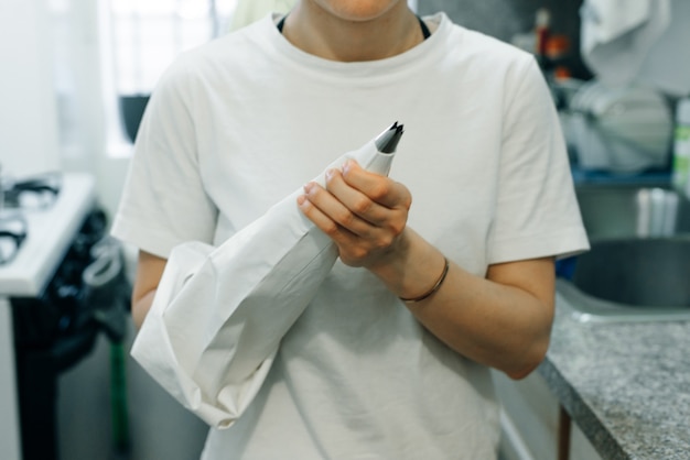 wonan holding white piping bag on the kitchen.