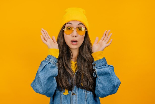 Wonder asian woman in yellow hat and sunglasses looking in excitement