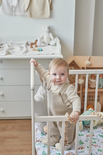 Wonderful baby boy with blue eyes in crib Child playing with toys in nursery Early development kindergarten nursery playroom Children's Day Mother's Day