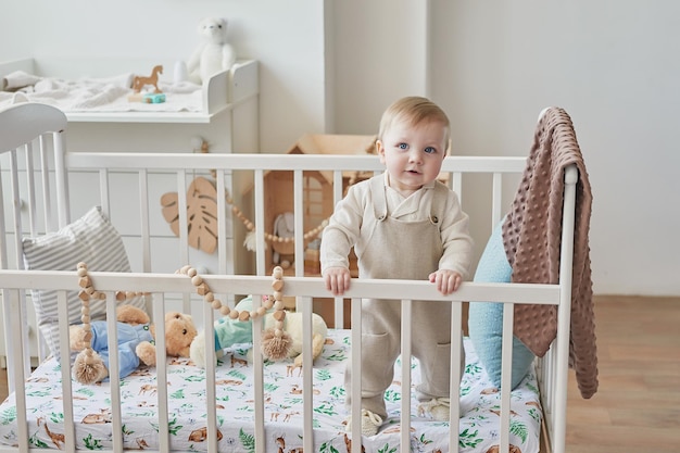 Wonderful baby boy with blue eyes in crib Child playing with toys in nursery Early development kindergarten nursery playroom Children's Day Mother's Day