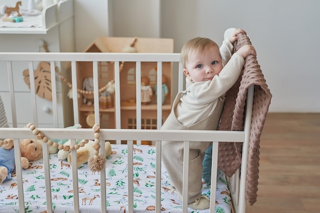 Wonderful baby boy with blue eyes in crib Child playing with toys in nursery Early development kindergarten nursery playroom Children's Day Mother's Day