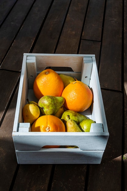 Foto una meravigliosa e bella scatola di legno piena di frutta fresca su una superficie di legno marrone scuro