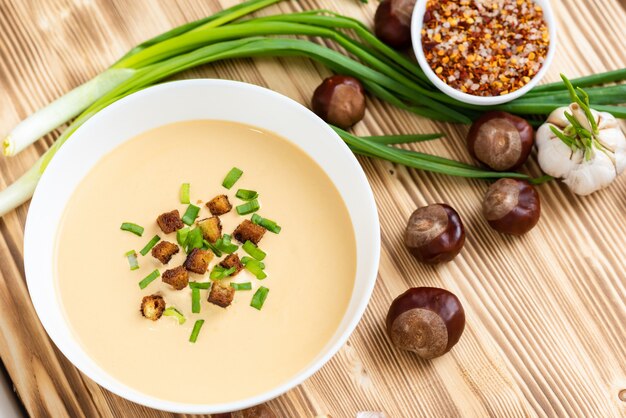 Wonderful cream soup of chestnuts on a wooden table.