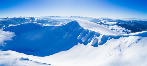 晴れた凍るような冬の日に雪に覆われた山の丘の上の素晴らしい巨大な雪の吹きだまり