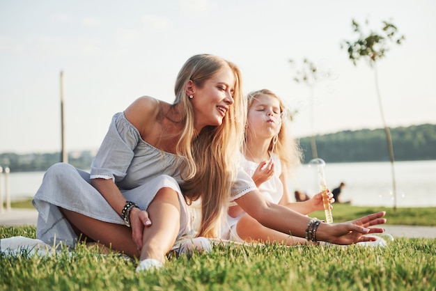 A wonderful girl child makes bubbles with her mom in the park.