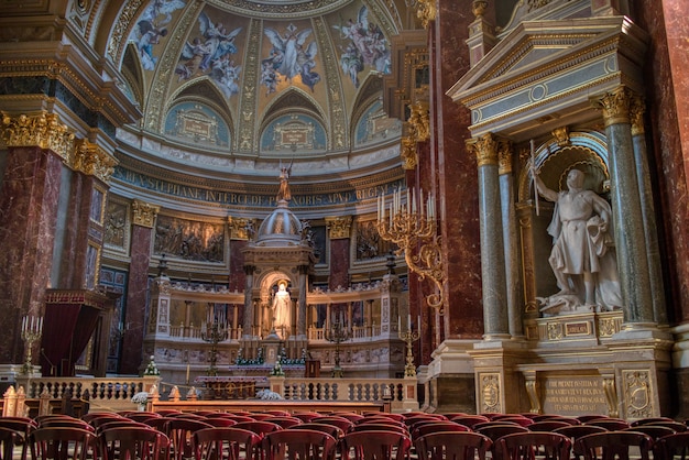 Wonderful interior of Catholic Cathedral with colorful painting on the walls and marble statues and sculptures in Budapest, Hungary.