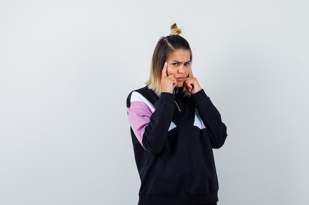 Wonderful lady keeping fingers on temples in sweatshirt and looking displeased