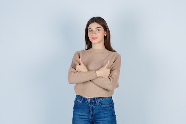Wonderful lady showing thumbs up in sweater, jeans and looking cheerful , front view.