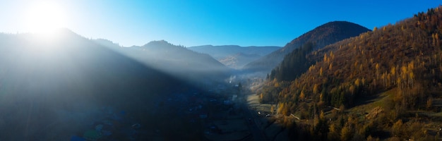 Wonderful mountain landscape. Dawn in the autumn Carpathians, the sun's rays shining on the fog and yellow autumn trees. Drone view.