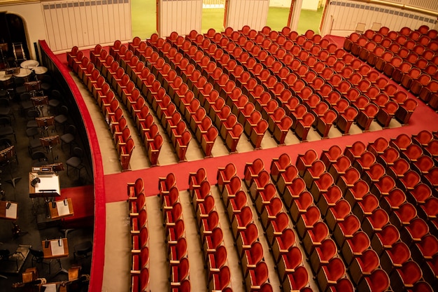 Photo wonderful view of the theatre concert hall of vienna state opera auditorium in vienna, austria - empty parterre with red seats in the rows without people and part of the orchestra pit.