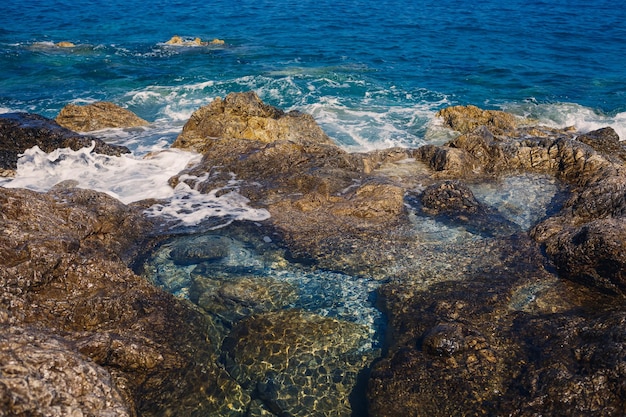青い地中海の素晴らしい景色日当たりの良い岩が泡と水しぶきで波を打ちます波は岸の岩に衝突します