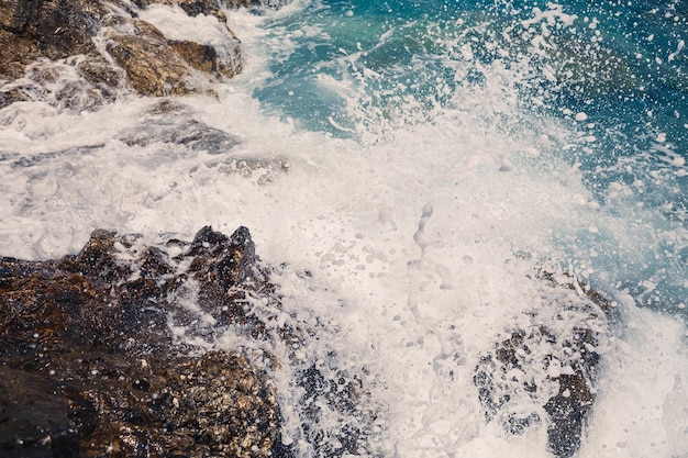 Wonderful views of the blue Mediterranean Sea Sunny rocks waves with foam and splashing water The wave crashes into the rocks on the shore