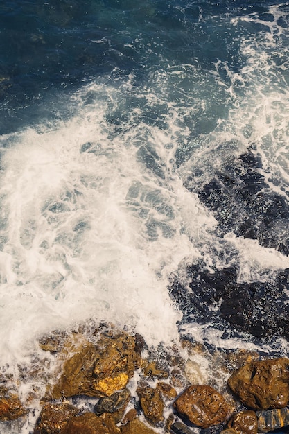 青い地中海の素晴らしい景色日当たりの良い岩が泡と水しぶきで波を打ちます波は岸の岩に衝突します