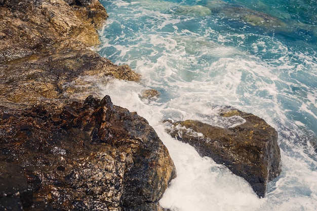 푸른 지중해 써니의 멋진 전망은 거품과 튀는 물로 파도가 해안의 바위에 충돌합니다